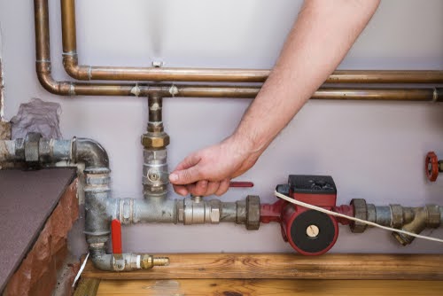 Employee's hand turning on or turning off water supply in the boiler room. Commercial plumbing company. 